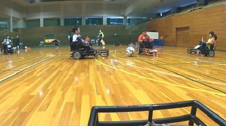 電動車椅子サッカーの試合の様子 - フットガードを使ったプレー